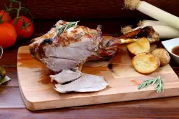 Pieczona jagnięcina z ziemniakami i rozmarynem na desce.