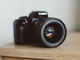 Czarna lustrzanka Canon z obiektywem EF LENS ULTRASONIC na drewnianym blacie.