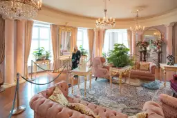 Elegancki salon z różowymi sofami i kryształowymi żyrandolami. Marzenie o noclegu w zamku staje się rzeczywistością.