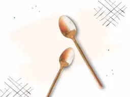 Dwie złote łyżeczki na jasnym tle z zielonymi kropkami i czarnymi liniami.