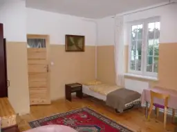 Pokój z łóżkiem, szafką nocną, drzwiami, oknem i dywanem.