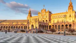 Plac Hiszpański w Sewilli o zachodzie słońca, z łukami i wieżami.