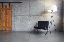 Drewniane drzwi przesuwne, czarne krzesło i lampa stojąca na tle betonowej ściany.