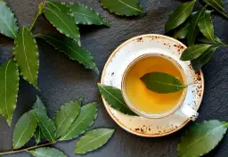 Aromatic napar z liści laurowych w filiżance, otoczony świeżymi liśćmi laurowymi na ciemnym tle.