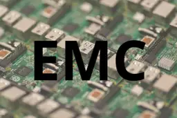 Na zielonej płytce drukowanej z widocznymi elementami elektronicznymi, wielkimi czarnymi literami widnieje napis "EMC". To skrót od Electromagnetic Compatibility, czyli kompatybilności elektromagnetycznej.