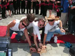 Trzej mężczyźni w białych koszulkach i zniszczonych jeansach składają dłonie na gwieździe. Tekst piosenki zawsze tam gdzie ty.