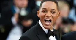 Will Smith w czarnym smokingu z muszką, uśmiecha się szeroko. Ciekawe, ile lat ma Will Smith, patrząc na jego energię!
