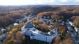 Widok z lotu ptaka na ośrodek rekolekcyjny otoczony jesiennym lasem.