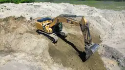 Żółta koparka CAT pracuje na budowie. Zastanawiasz się, ile kosztują uprawnienia na koparki?