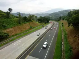 Droga ekspresowa z ruchem samochodów, otoczona zielonymi wzgórzami. Planujesz podróż i zastanawiasz się, jak zapłacić za autostradę A4?