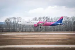 Samolot Wizz Air z wysuniętym podwoziem ląduje na pasie startowym.