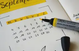 Zbliżenie na kalendarz z zaznaczonymi dniami i markerem.