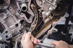 Mechanik pracuje przy rozrządzie silnika. Wymiana poduszki silnika może być konieczna, gdy pojawią się objawy takie jak wibracje.