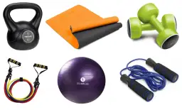 Kettlebell, mata, zielone hantle, piłka gimnastyczna, skakanka i gumy oporowe – kompletny zestaw domowy sprzęt do ćwiczeń.