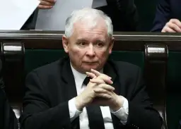 Jarosław Kaczyński w garniturze z splecionymi dłońmi, siedzi w ławach sejmowych.