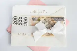 Elegancka koperta z napisem "Młodej Parze", ozdobiona banknotami 200 zł i białą wstążką. Idealny sposób, jak udokumentować pieniądze z wesela.