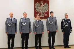 Pięciu policjantów w mundurach stoi w rzędzie przed godłem Polski.