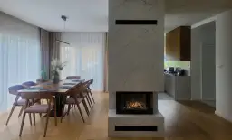 Nowoczesny kominek z marmuru, jak ozdobić komin w pokoju. Obok stół z krzesłami i kuchnia.