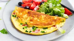 Złocisty omlet z warzywami i sałatką na talerzu.