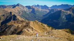 Widok na malowniczą przełęcz pod Kopą Kondracką. Szlak turystyczny wije się pośród złotych traw i skalistych zboczy, prowadząc w głąb gór.