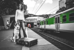 Kobieta z psem na peronie czeka na pociąg. Zastanawia się, ile kosztuje bilet dla psa w pociągu, by móc podróżować razem.