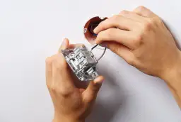 Instalacja podwójnego włącznika światła 2 kable. Dłonie montują mechanizm w puszce, podłączając przewody.
