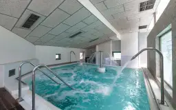 Piscina de hidromasaje con chorros de agua y cascada central en un balneario.