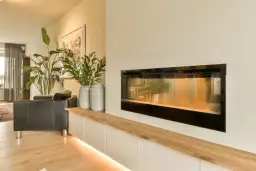 Nowoczesny kominek z podświetlaną półką i roślinami to świetny pomysł, jak udekorować kominek.