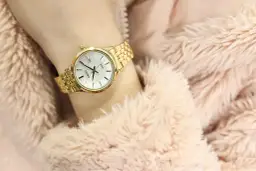 Złoty zegarek damski Seiko na nadgarstku, otoczony różowym futerkiem.