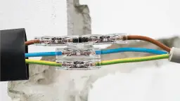 Łączenie kabli w ścianie bez puszki za pomocą złączek WAGO. Brązowy, niebieski i żółto-zielony przewód połączone w estetyczny sposób.