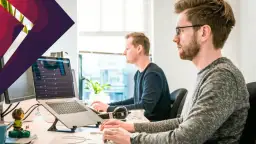 Dwóch mężczyzn pracuje przy komputerach w biurze.