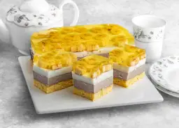 Pyszne bananowiec ciasto z galaretką i bananami, pokrojone na porcje. Obok czajniczek i filiżanka.