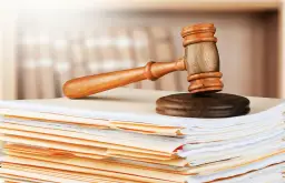 Młotek sędziowski na stercie dokumentów. Dowiedz się, jak sprawdzić czy pozew został złożony i jakie kroki podjąć.