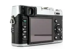 Tył aparatu Fujifilm X100S z widocznym ekranem, przyciskami sterującymi i pokrętłami.