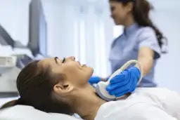 Badanie USG szyi, kluczowe dla diagnostyki tarczycy. Lekarz wykonuje badanie, by ocenić stan tarczycy, a jod jest ważnym pierwiastkiem dla jej prawidłowego funkcjonowania.