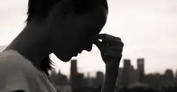 Sylwetka kobiety z dłonią na czole, zamyślona. Czy to objawy depresji? Test 9 pytań może pomóc.