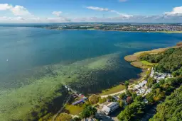 Widok z lotu ptaka na zatokę z pomostem, łodziami, kempingiem i lasem.