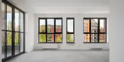 Puste mieszkanie z dużymi oknami wychodzącymi na nowoczesne budynki. Zastanawiasz się, co to jest odstępne za mieszkanie?