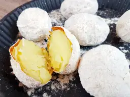 Ziemniaki pieczone w popiele, jeden przekrojony na pół, ukazujący miękki środek.