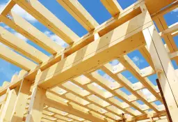 Konstrukcja domu szkieletowego z drewna pod błękitnym niebem. Zastanawiasz się, ile kosztuje postawienie domu szkieletowego?