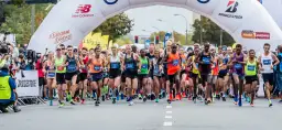 Start maratonu dla amatora. Zawodnicy pod łukiem startowym, tłum kibiców i kamerzystów.