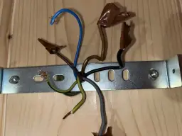 Instrukcja jak podłączyć kinkiet: przewody fazowy (brązowy), neutralny (niebieski) i ochronny (zielono-żółty) czekają na połączenie.