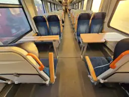 Pociąg do Pragi. Puste siedzenia z niebieskimi obiciami i stolikami czekają na pasażerów.