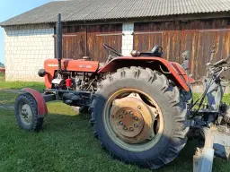 Czerwony Ursus C-330M na trawie, gotowy do pracy. Warto sprawdzić, ile powietrza w oponach Ursus C-360, by zapewnić optymalną przyczepność.