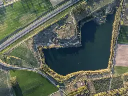 Widok z lotu ptaka na jezioro otoczone polami i drogą.