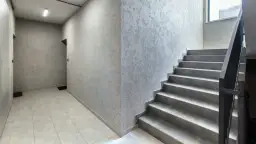 Nowoczesna klatka schodowa z szarymi stopniami i ozdobnymi ścianami.
