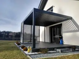 Nowoczesna pergola z ruchomymi lamelami, taras z grillem i butlą gazową. Zastanawiasz się, ile kosztuje zrobienie pergoli?
