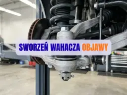 Widok na element zawieszenia samochodu, gdzie widoczny jest sworzeń wahacza. Objawy jego zużycia mogą prowadzić do problemów z prowadzeniem pojazdu.