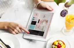 Kobieta przegląda tablet z ofertami, szukając inspiracji, jak zarabiać na reklamach. Obok deser i napój.