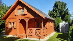 Drewniany domek na zgłoszenie, idealny na wynajem. Otoczony zielenią, z werandą i schowkiem.